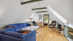 Ett rum i loftstil med en blå soffa, ett matbord i trä och en svart läderstol.