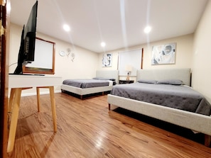 Un dormitorio con dos camas, un escritorio, un televisor y obras de arte en las paredes.