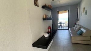 Ein modernes Wohnzimmer mit einer Couch, einem Couchtisch und einer Küchenzeile mit Regalen.