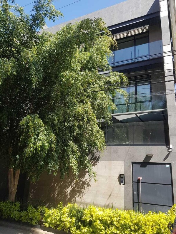 Un edificio moderno con un gran árbol en primer plano.