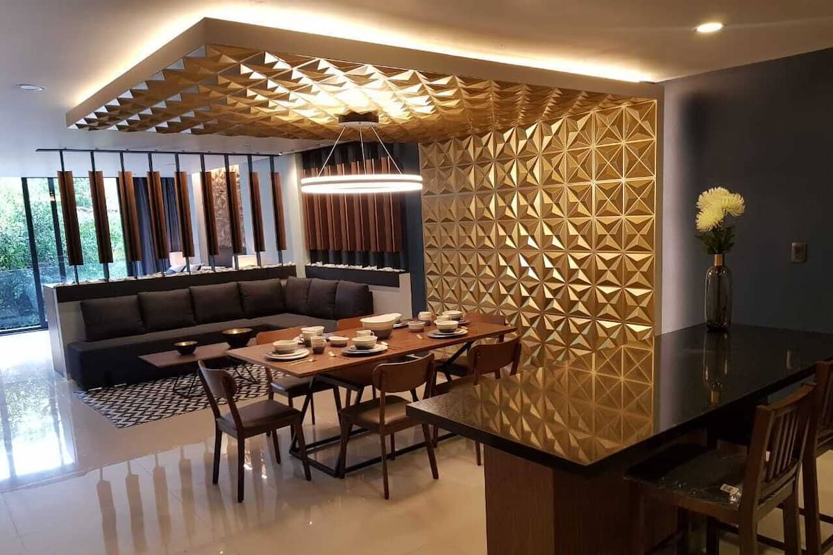A modern dining area with a geometric-patterned wall, a black dining table, and wooden chairs.