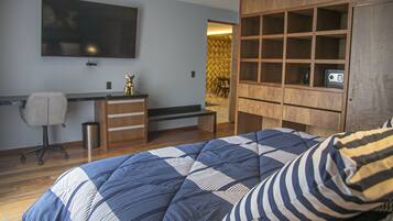 Quarto com cama, escrivaninha, cadeira, televisão e guarda-roupa.