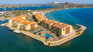 Un hôtel situé sur la côte, composé de plusieurs bâtiments, doté d’une piscine et d’un port de plaisance avec des bateaux.