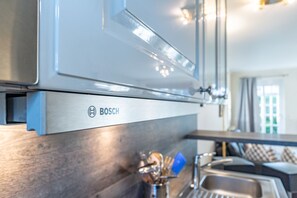 Une cuisine équipée d’une hotte de marque Bosch, d’appareils électroménagers en acier inoxydable et dotée d’un design moderne.