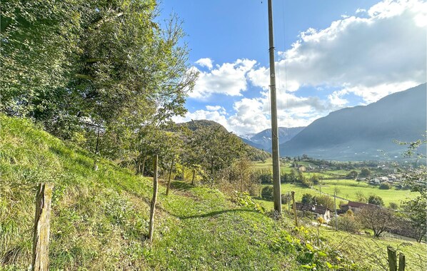 Paisatge rural amb vista a una vall, cases i muntanyes al fons.