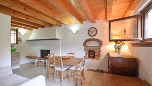 A cozy room with a wooden ceiling, a fireplace, a dining table with chairs, and a bed. - Nice home in Feltre with WiFi (Feltre)