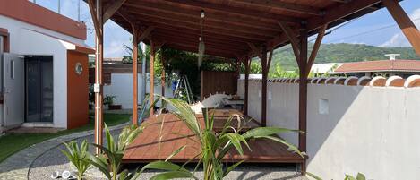 A covered patio area with a wooden ceiling, potted plants, and a gravel ground.