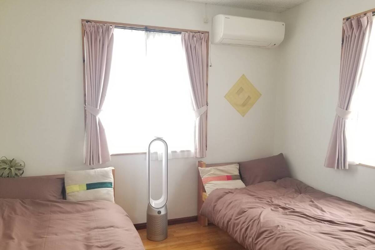 A bedroom with two beds, a standing heater, and an air conditioning unit.