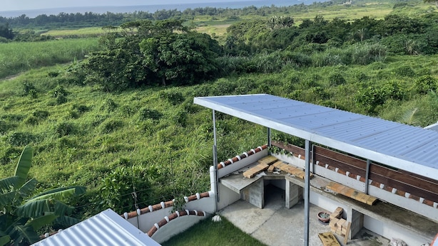 Un panneau solaire installé sur un bâtiment, offrant une vue sur un paysage verdoyant et luxuriant et sur une étendue d’eau lointaine.