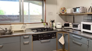 Une cuisine moderne équipée d’une cuisinière à gaz, d’un lave-vaisselle encastré et de divers appareils, notamment un cuiseur à riz et des grille-pain.