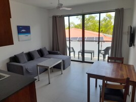 Un soggiorno moderno con un divano grigio, un tavolo da pranzo in legno e una TV a parete.