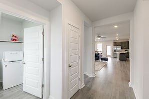 Una cocina moderna con una isla central, una zona de comedor con mesa y sillas, y un pasillo que conduce a una sala de estar.
