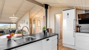 Een moderne keuken met een groot schiereiland, ingebouwde apparatuur en uitzicht op de omgeving.
