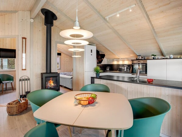 A modern kitchen with a central island, a dining area with a table and chairs, and a visible wood-burning stove. - "Holmwith" - 50m from the sea by Interhome (Esbjerg V)