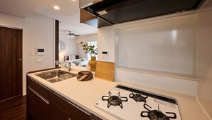 A modern kitchen with a white countertop, stainless steel sink, and a gas stove. - Casa YONNA Naha (Naha)