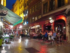 Un espace de restauration en plein air, avec des tables et des chaises, entouré de bâtiments dont les enseignes sont illuminées.