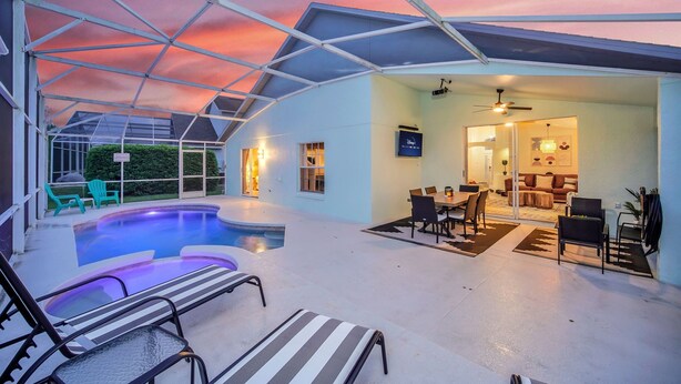 A covered outdoor area with a swimming pool, lounge chairs, and a dining area. - Amazing Disney Villa | Pool&Spa | Gameroom (Kissimmee)