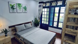 Un dormitorio con una cama de madera, una mesita de noche con lámpara y una ventana con cortinas.