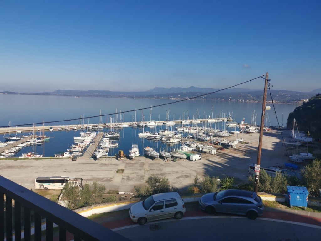 A marina with numerous boats docked, a clear sky, and a distant view of mountains.