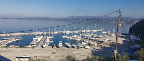 A marina with numerous boats docked, a clear sky, and a distant view of mountains.