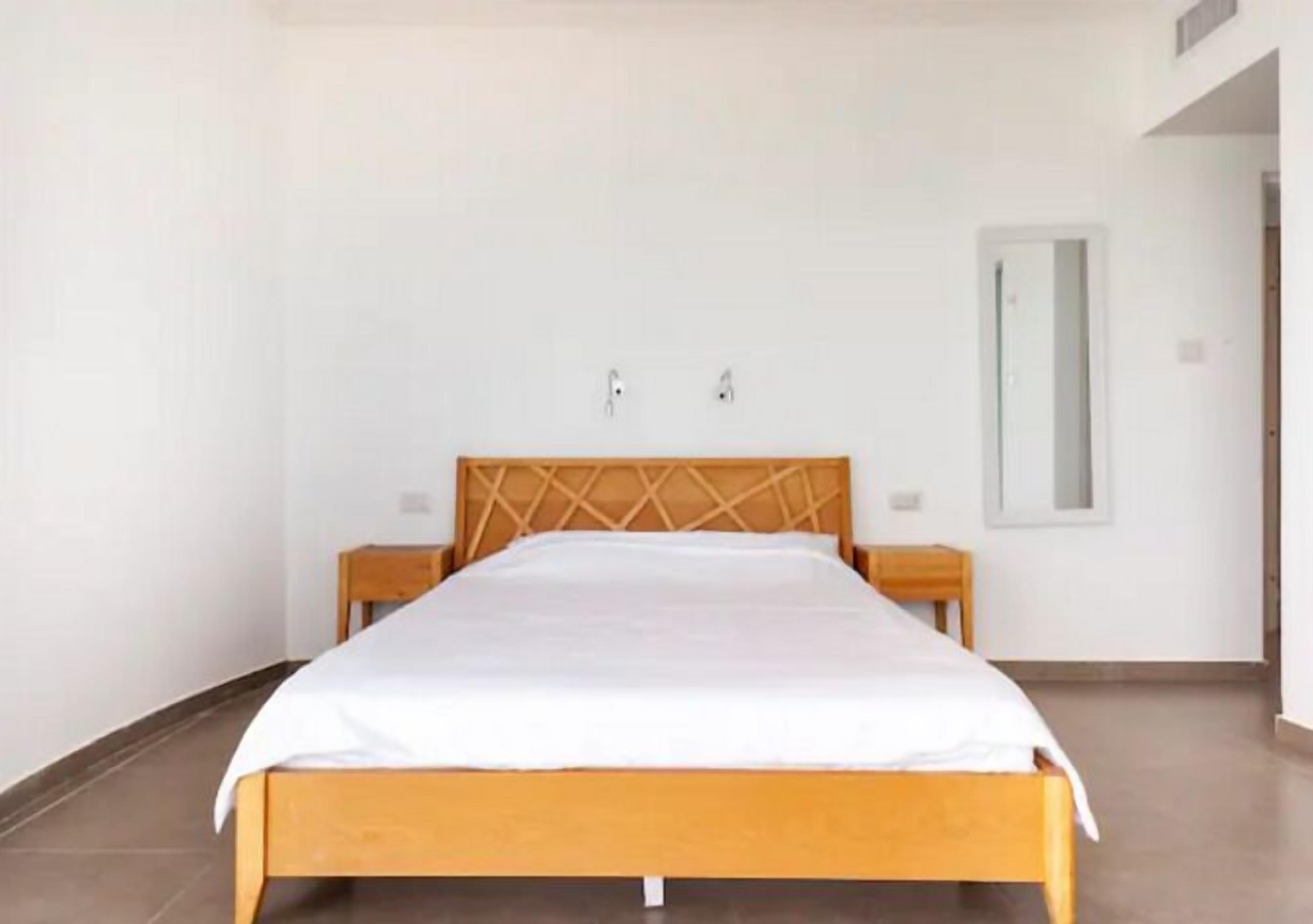 A bedroom with a wooden bed, two bedside tables, and a large mirror on the wall.
