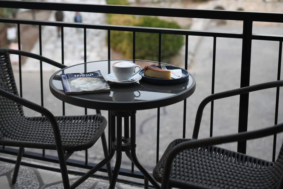 A balcony with a table, chairs, and a view of a historic stone building.