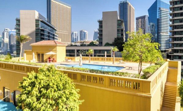 Ein modernes Gebäude mit Schwimmbecken, umgeben von Grünflächen und Hochhäusern im Hintergrund.