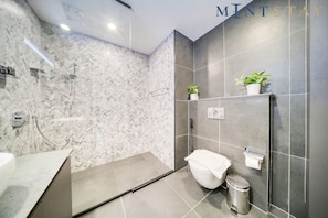 A modern bathroom with a shower, toilet, and sink.