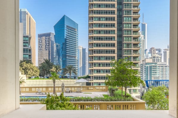 A modern urban skyline with high-rise buildings, a well-maintained public square with seating, and greenery.