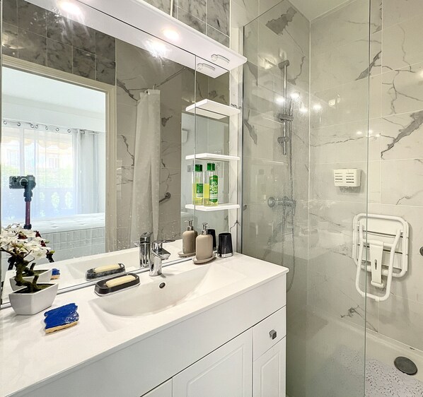 A modern bathroom with a large mirror, a sink, and a glass shower enclosure. - Central Location, Close to Beaches, Pool, Gym, Sauna, Parking, WiFi, A/C (Menton)