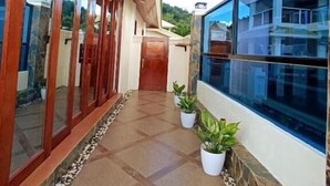 Un pasillo con suelo de baldosas, puertas de madera y plantas en macetas.