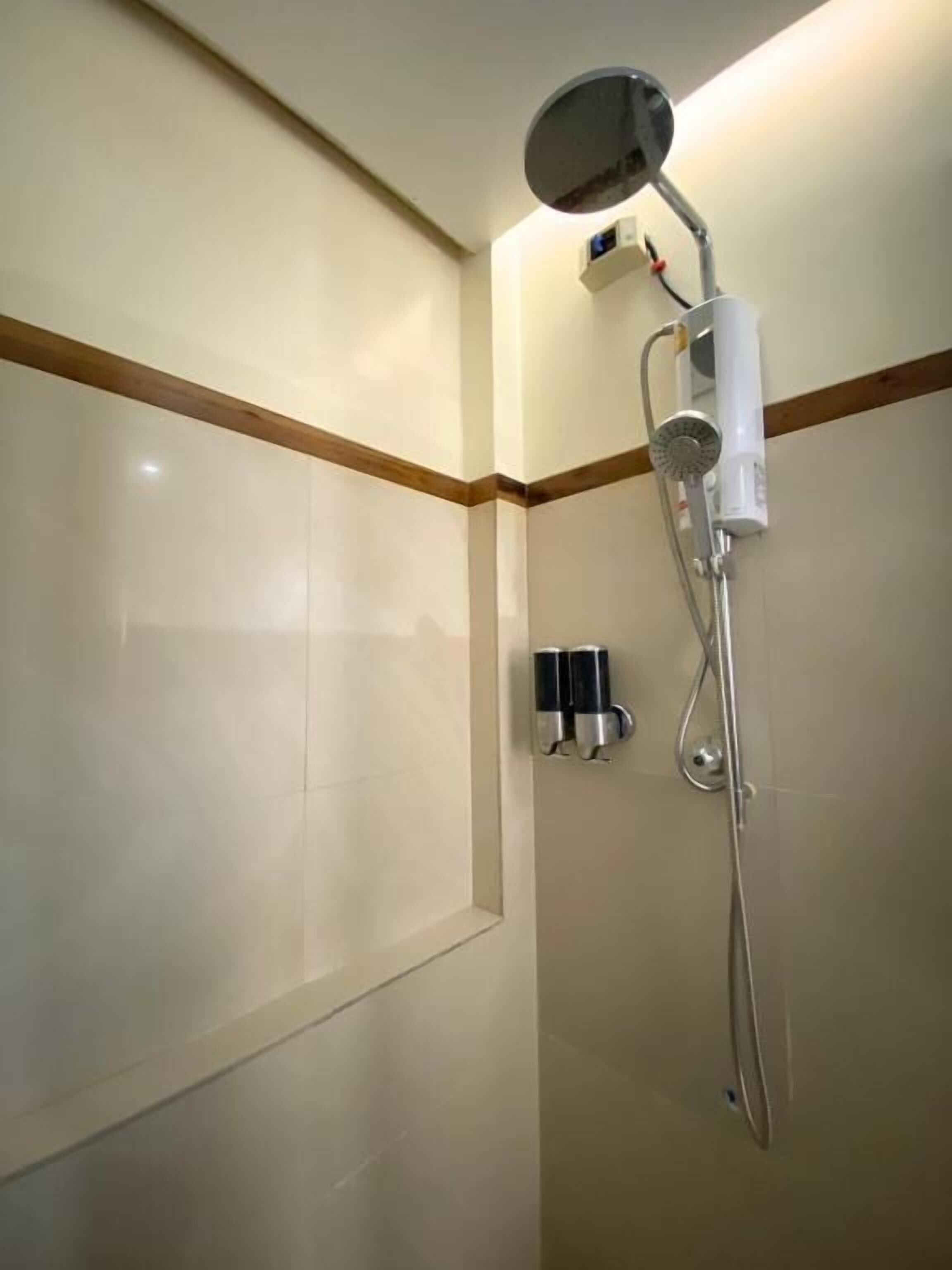 Een douche met een handdouche, een bedieningspaneel aan de muur en een handdoekdispenser.