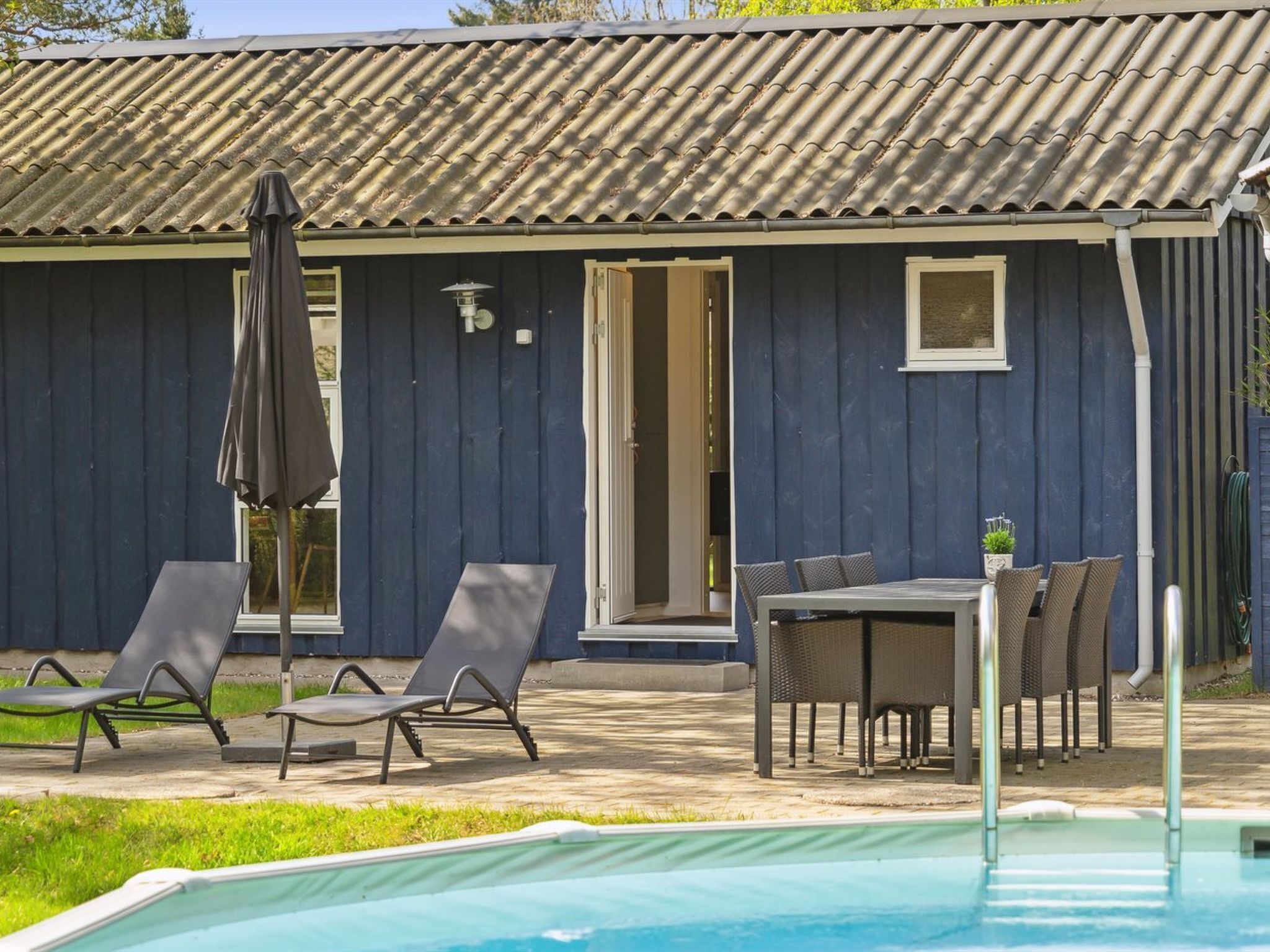 A poolside area with lounge chairs, a table, and an umbrella.
