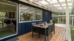 A covered patio with a wooden deck, a table with chairs, and a large window overlooking a garden. - "Esmer" - 8km from the sea by Interhome (Ebeltoft)