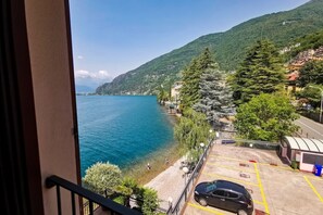 Un balcó amb vista a un llac, una zona de pàrquing i un paisatge de muntanya.