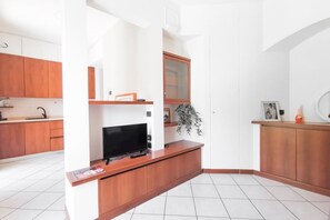 Una cuina moderna amb armaris de fusta, televisió integrada i una petita planta.
