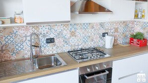 Et moderne køkken med stålvask, gasblus og et mønstret backsplash.