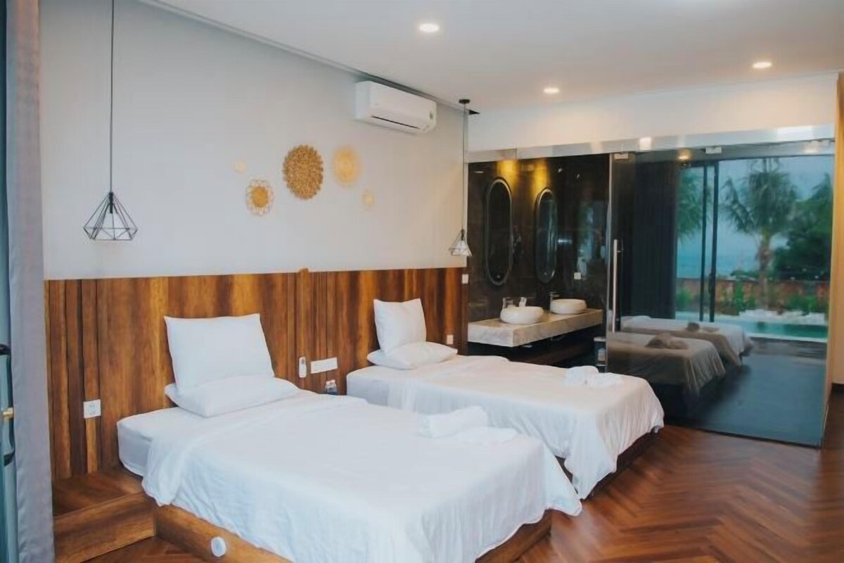 Ein modernes Hotelzimmer mit zwei Betten, einem Holzkopfende, einem großen Spiegel und Blick ins Freie.