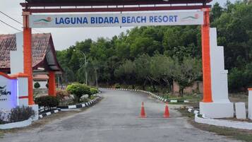 The entrance to Laguna Bidara Beach Resort with a sign above the gate and a pathway leading to the building.