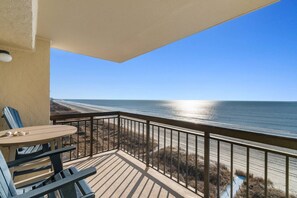 A balcony with a view of the beach and ocean.