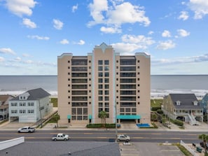 Ein mehrstöckiges Hotel mit zentralem Eingang, nahe am Strand und mit Blick auf das Meer.