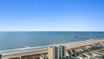 A coastal area with a beach, a pier, and residential buildings.