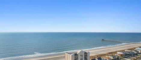 A coastal area with a beach, a pier, and residential buildings.