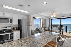 A modern kitchen with white cabinets, stainless steel appliances, and a large island.