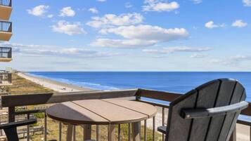 A balcony with a view of the beach and ocean.