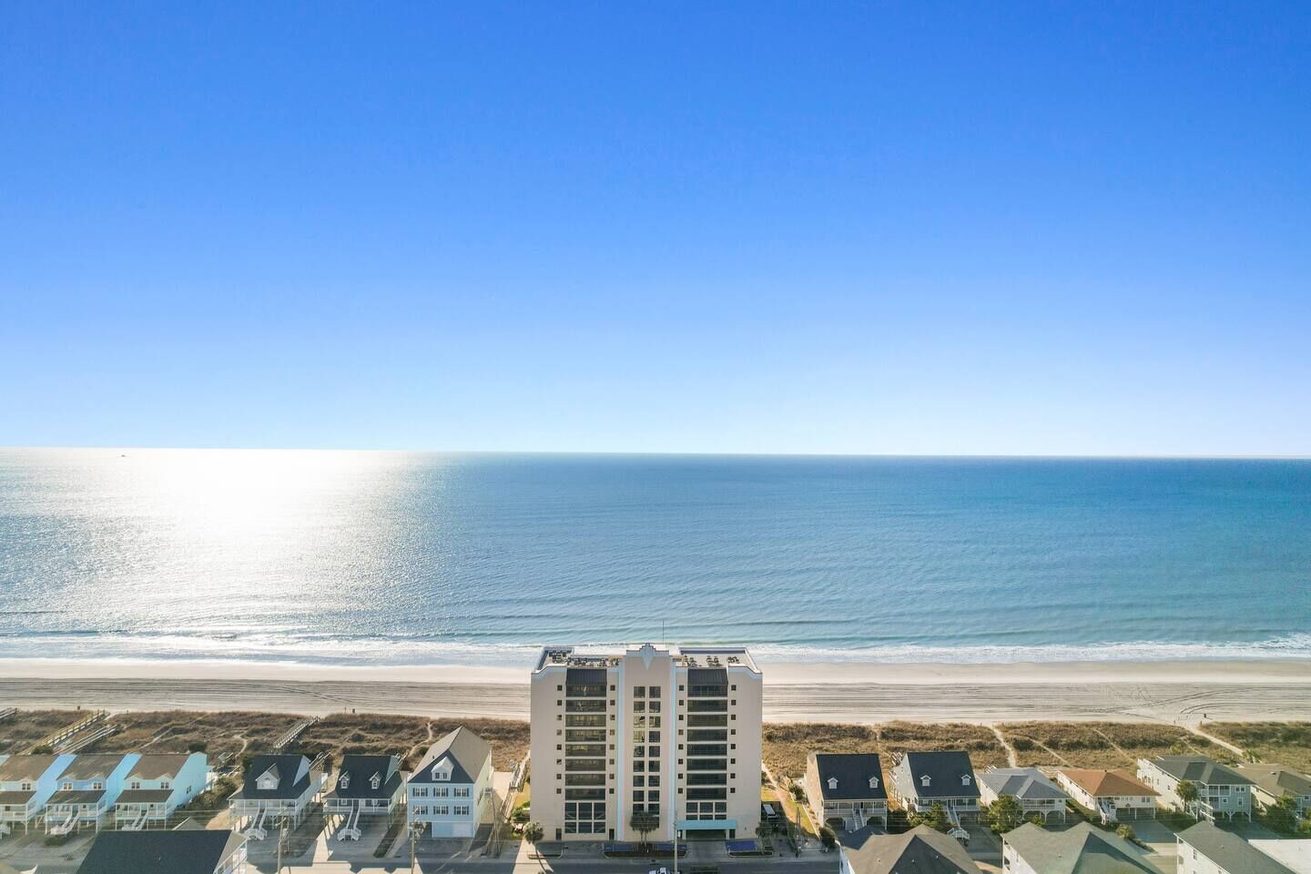 Un hôtel situé en bord de mer, offrant une vue sur l’océan, avec des bâtiments à plusieurs étages et un espace de stationnement.