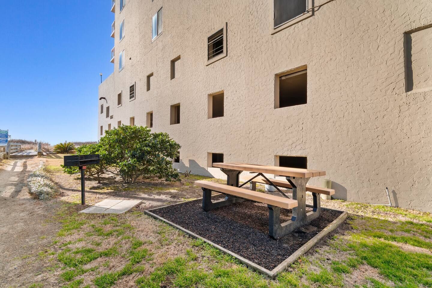 A building with a flat facade, multiple windows, and a picnic table in the foreground.