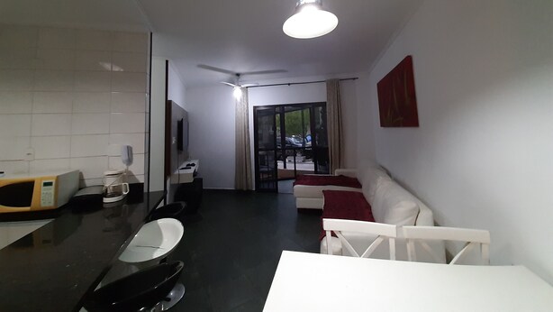 Un salon moderne avec un coin repas, un ventilateur de plafond et une vue à travers une porte vitrée.