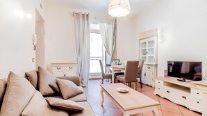 A modern living room with a sofa, coffee table, TV, and dining area. - Apartment located in the heart of Trastevere, a well-known central district of Rome.  (Roma)
