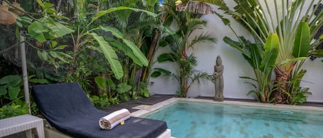 A poolside area with a lounge chair and a statue.